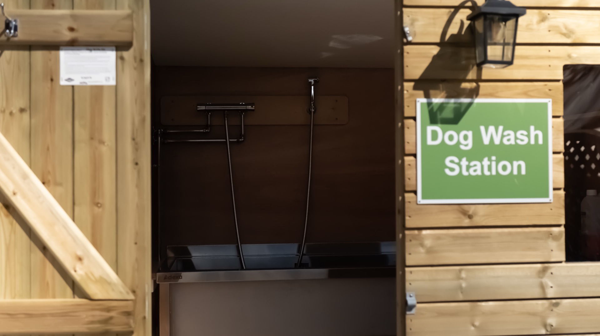 Open dog wash station shed with a stainless steel tub, wall-mounted taps and shower hoses
